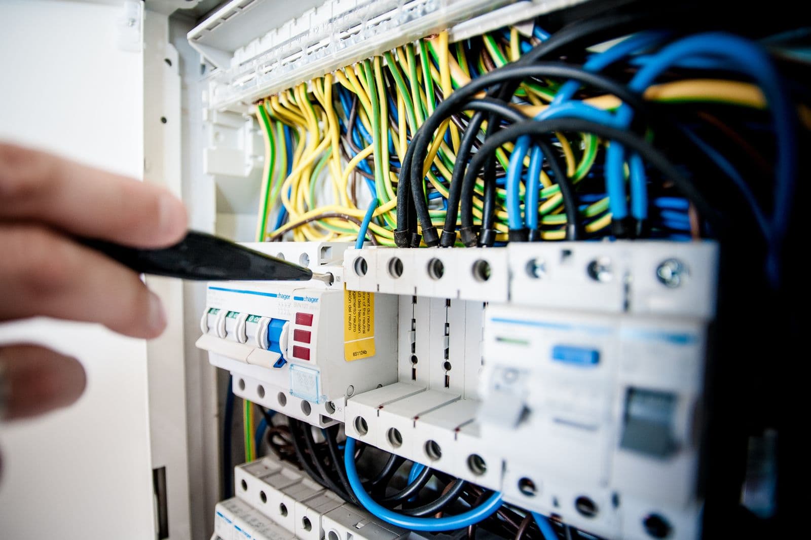Handen van een elektricien aan het werk in een groepenkast
